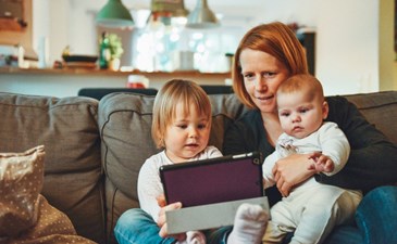 Mum and two small babies playing with a tablet computer