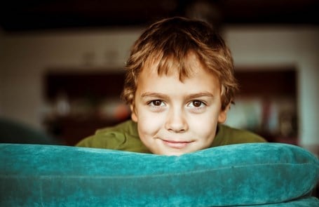 Smiling boy looks over the back of a sofa
