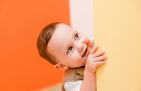 Smiling toddler peeping around a corner