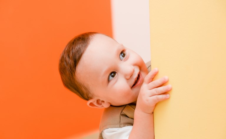 Smiling toddler peeping around a corner