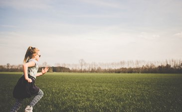 Happy girl running across an empty park